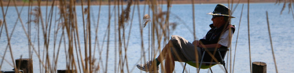 Mies istuu laiturilla