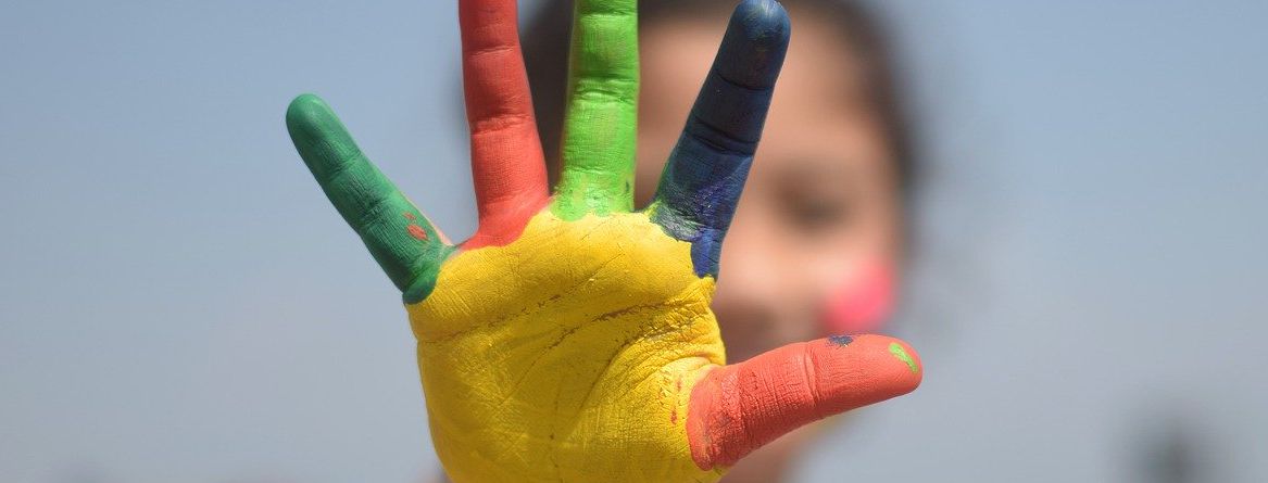 Lapsen käsi, joka on värjätty monilla väreillä