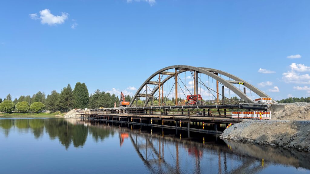 Kaarisilta yksikaarisena.  Ensimmäinen kaari on purettu. Sillalla työkoneita.