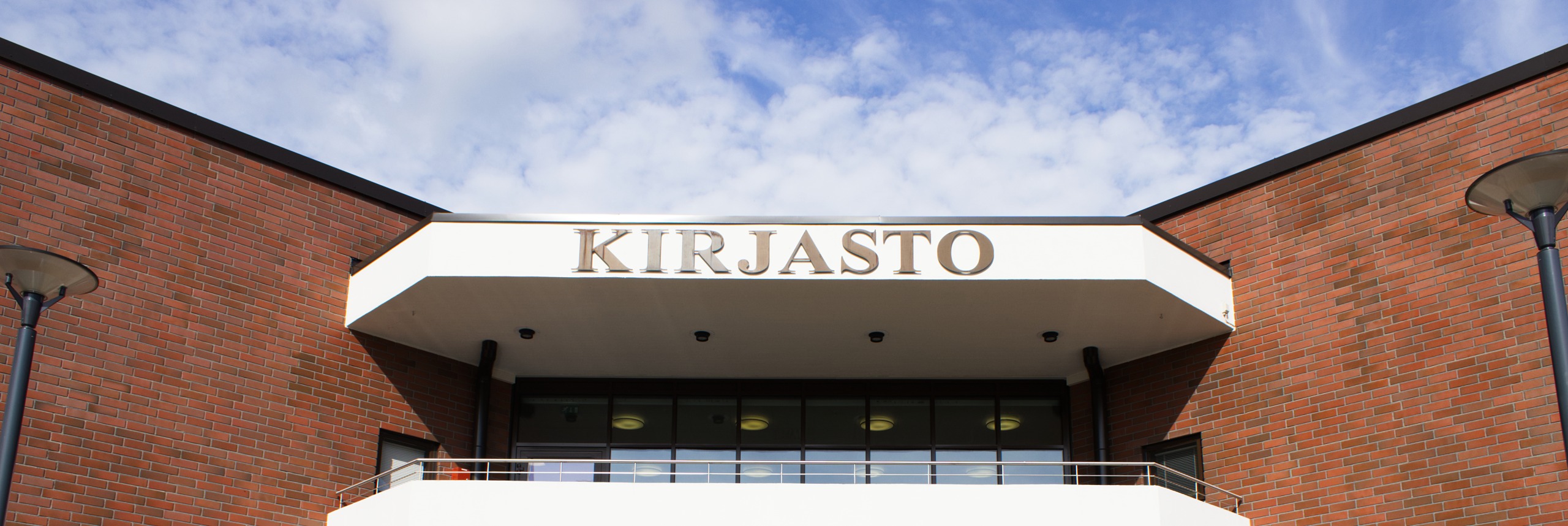 Lieksan kirjaston julkisivun Kirjasto-kyltti. Taustalla näkyy taivasta.