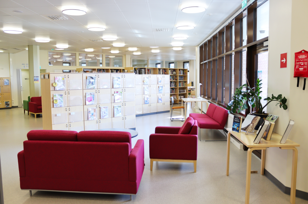 Lieksan kirjaston lehtiosastoa. Etualalla on sohvaryhmä. Kauempana on lehtikaappeja ja kirjahyllyjä.