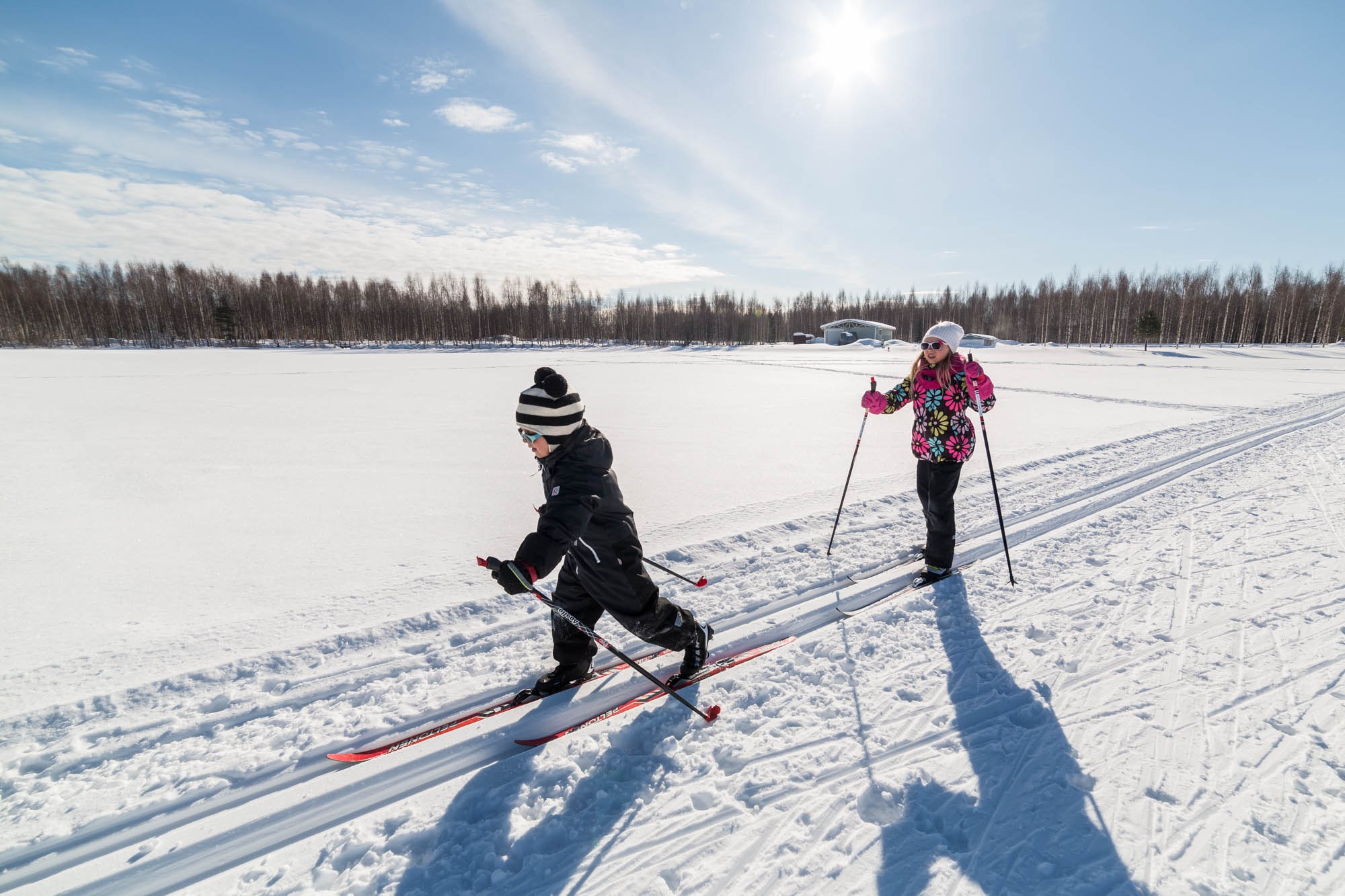 Kaksi lasta hiihtämässä aurinkoisella säällä hiihtoladulla